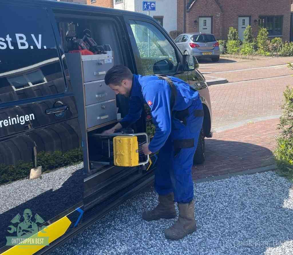Een monteur pakt apparatuur uit de bedrijfsbus voor service aan huis, het moment om een professional in te schakelen voor een verstopte wc in Best