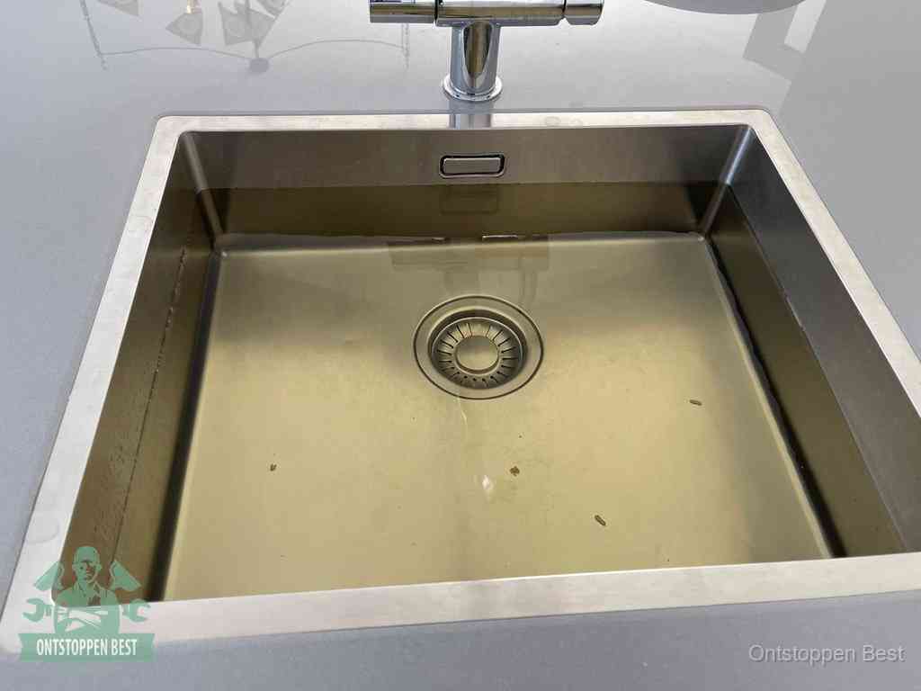 Stilstaand water in een rvs spoelbak dat niet wegloopt, een duidelijk signaal van een gootsteenverstopping in Best