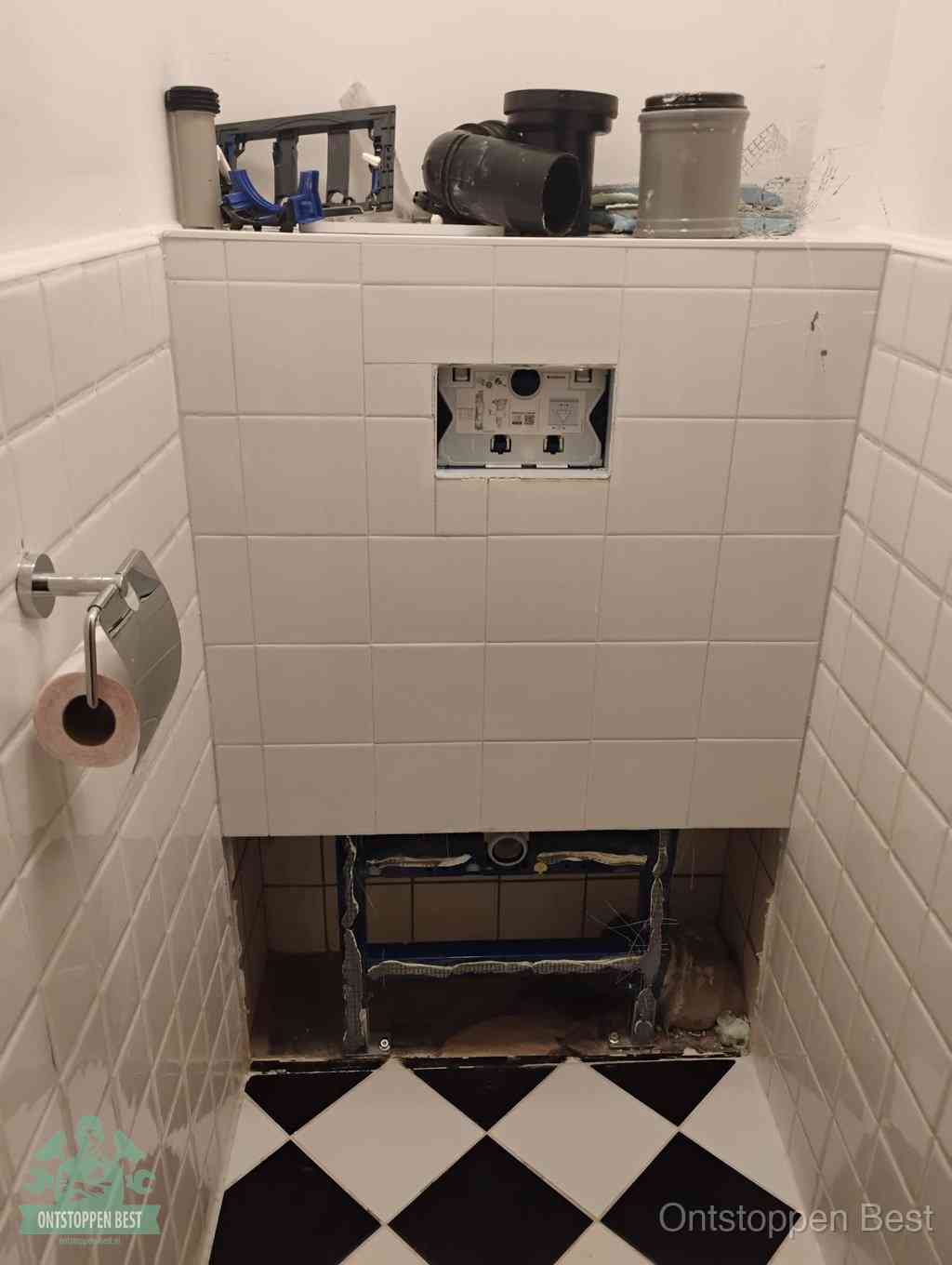 Een toiletruimte waar het hangtoilet en de inbouwreservoir-onderdelen zijn vrijgelegd voor onderhoud, periodiek nazicht voorkomt een wc-verstopping in Best